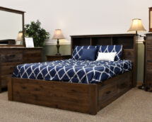 Lakeside Bungalow Bedroom is a dark wood bed frame with dark blue and white bead spread and pillows.